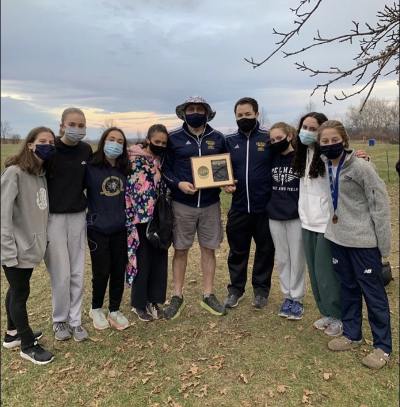 The girls varsity Cross Country team shares their league title victory with their coaches.