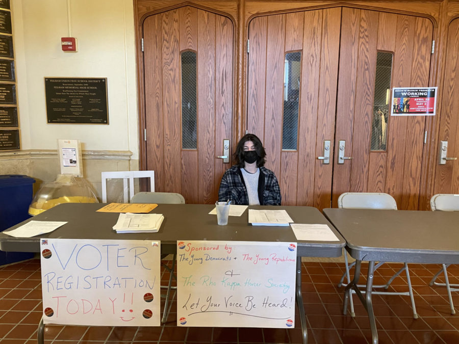 Manning the table during a free period, junior James Findikyan helps students sign up to perform their civic duty.